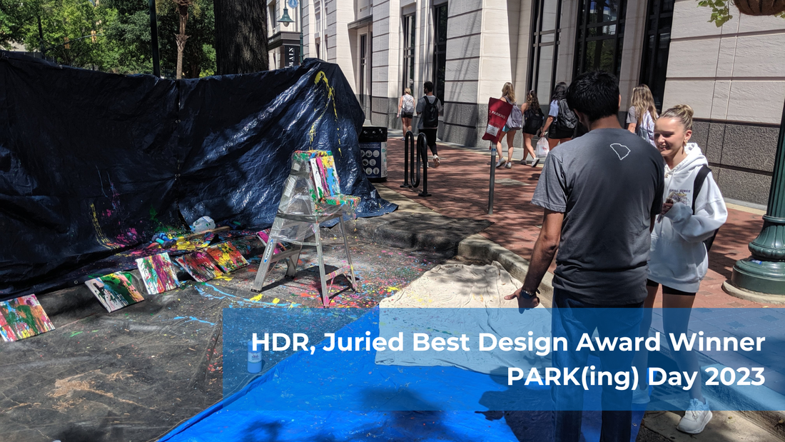 a man and a woman are talking in the foreground, standing in a parking space converted into a park, while a series of splatter painted canvases appear in the background.  Text reads: “HDR Juried Best Design Award Winner PARK(ing) Day 2023”.